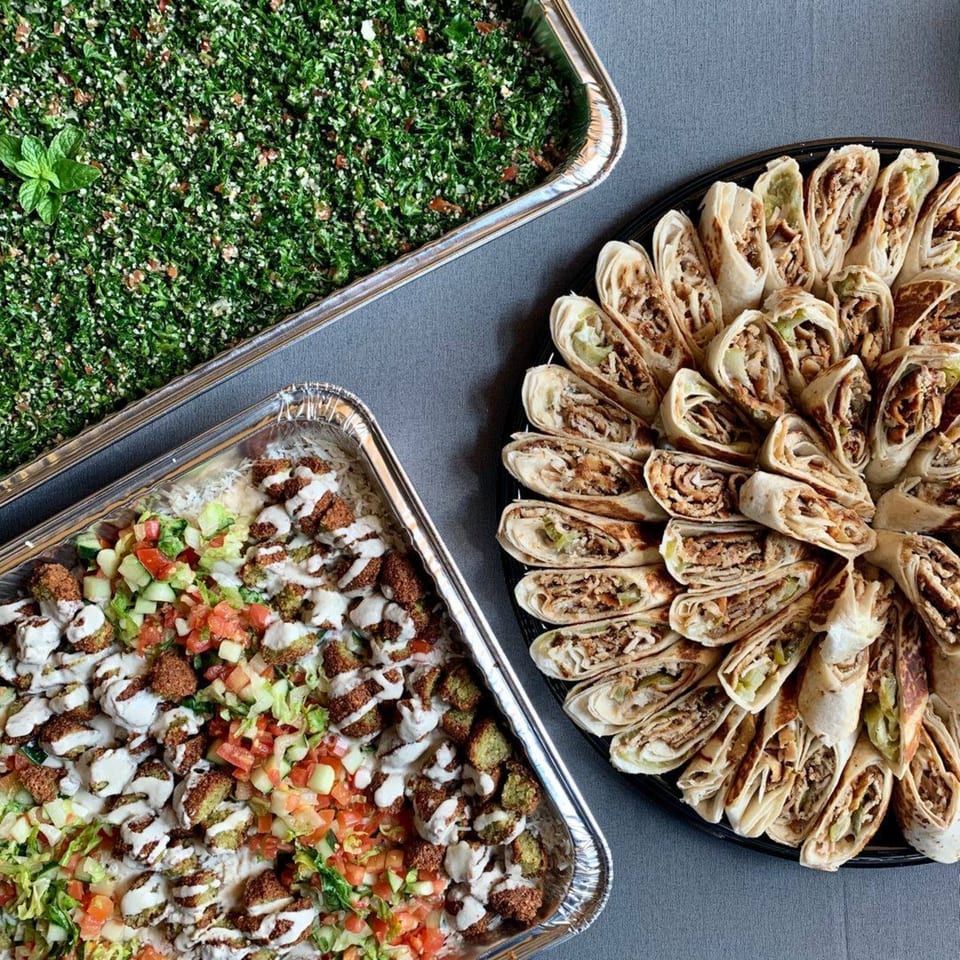 Catering spread with Shawarma Press falafel, tabbouleh, and chicken shawarma wraps.