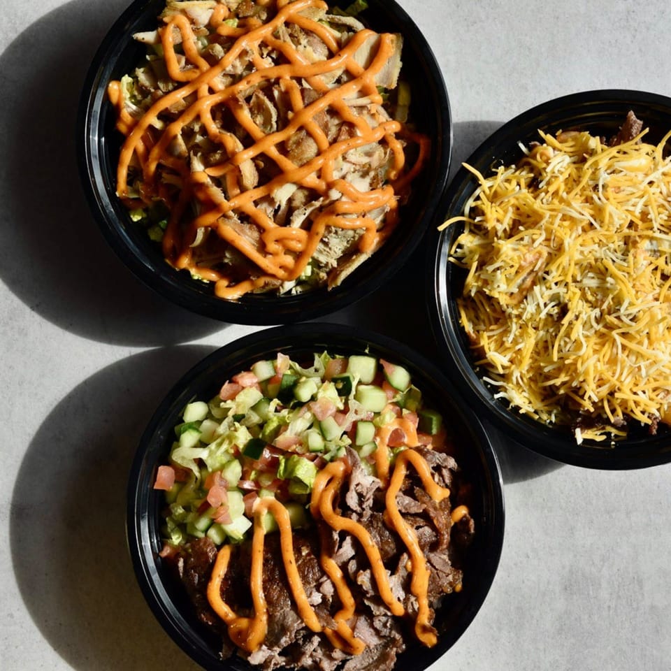 Three Shawarma Press bowls with chicken, beef, and cheese, drizzled with sauce.