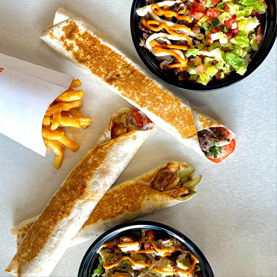 Shawarma Press Mediterranean wraps, bowls, and fries on a light surface.